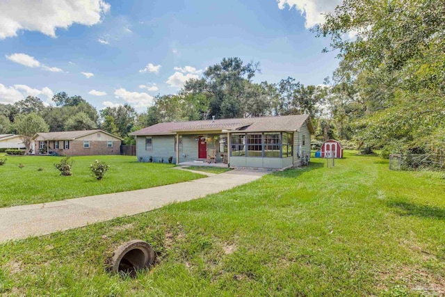 single story home with a storage shed, a sunroom, and a front yard