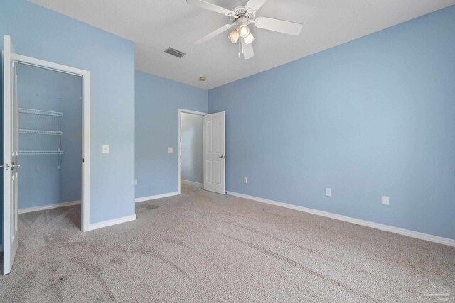 7008 Turnberry Cir, Navarre, FL 32566 - unfurnished bedroom featuring visible vents, ceiling fan, a closet, carpet, and a walk in closet