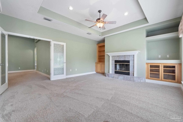 7008 Turnberry Cir, Navarre, FL 32566 - unfurnished living room featuring carpet, ceiling fan, a fireplace, baseboards, and a tray ceiling