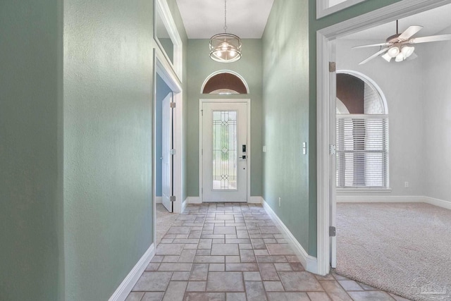 7008 Turnberry Cir, Navarre, FL 32566 - foyer entrance with stone tile flooring, a healthy amount of sunlight, a notable chandelier, and baseboards