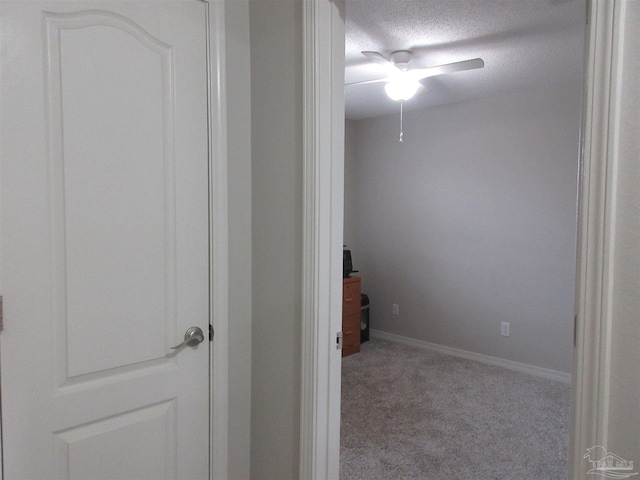 hall with light colored carpet and a textured ceiling