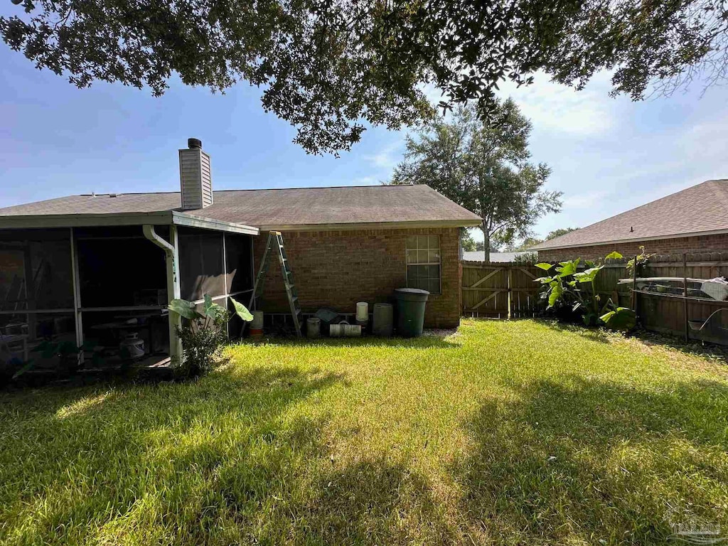 rear view of property featuring a sunroom and a lawn