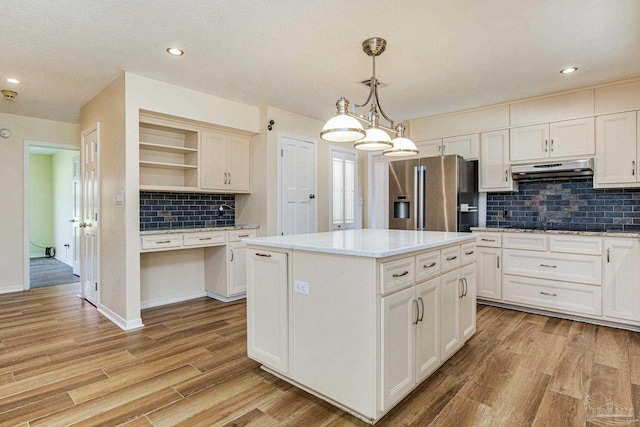 kitchen featuring pendant lighting, a center island, stainless steel refrigerator with ice dispenser, backsplash, and light hardwood / wood-style flooring