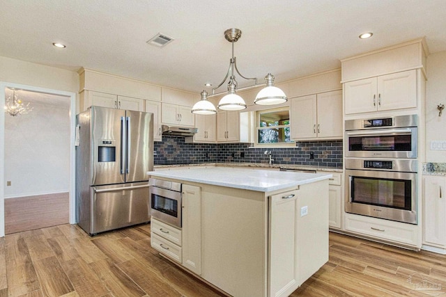 kitchen featuring pendant lighting, appliances with stainless steel finishes, a center island, and light wood-type flooring