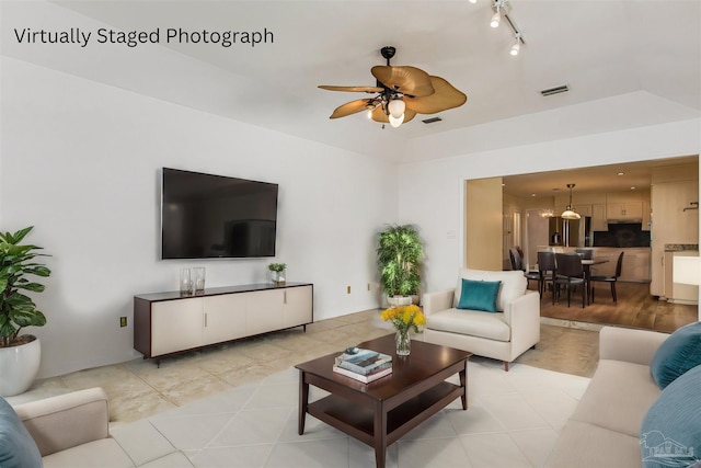 tiled living room with ceiling fan and track lighting