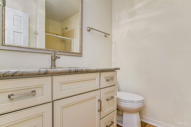 bathroom with a shower with shower door, hardwood / wood-style floors, toilet, and vanity