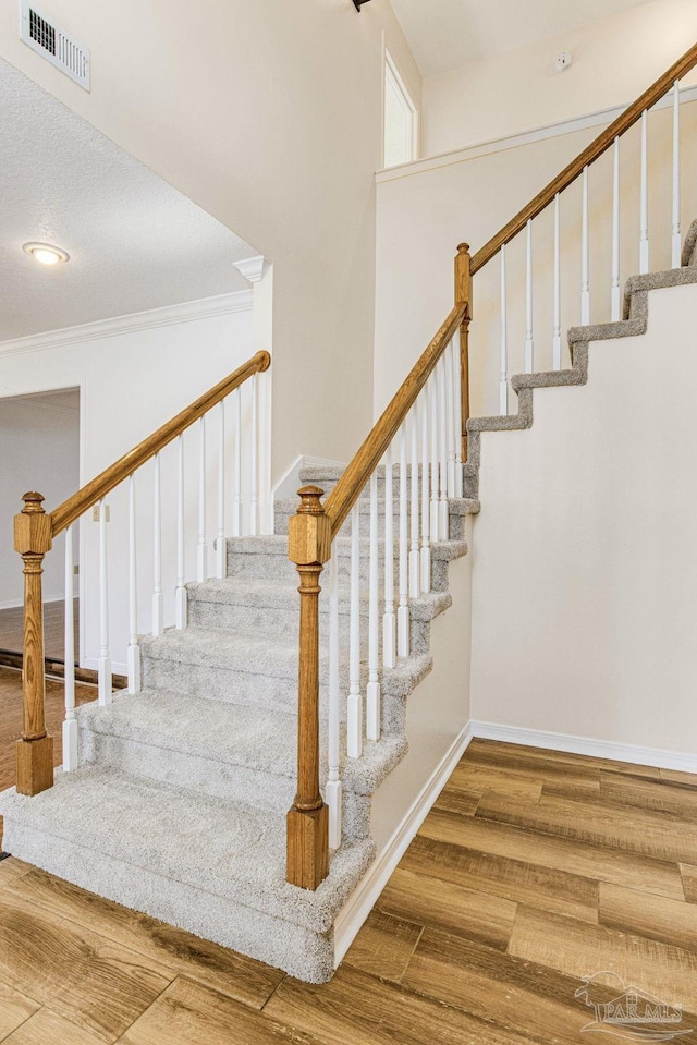 staircase featuring crown molding and hardwood / wood-style flooring