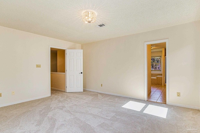 empty room featuring light colored carpet and a textured ceiling