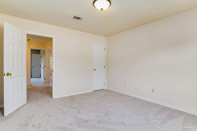 unfurnished room with light colored carpet and a textured ceiling