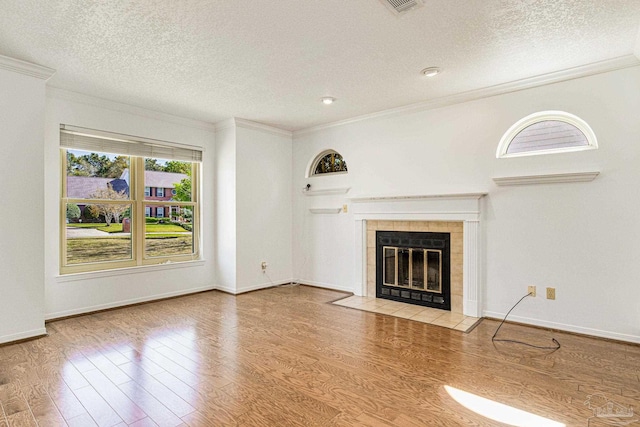 unfurnished living room with a textured ceiling, light hardwood / wood-style floors, a fireplace, and crown molding