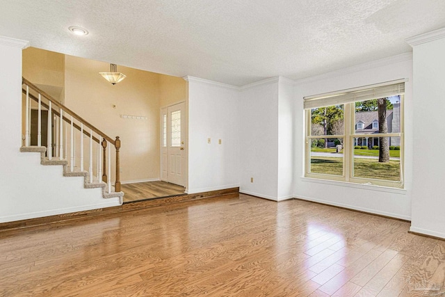 entrance foyer with ornamental molding, hardwood / wood-style floors, and a textured ceiling