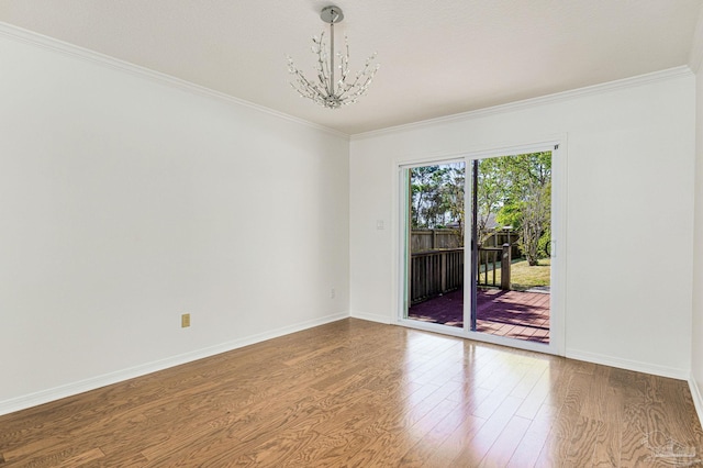 empty room featuring wood-type flooring, crown molding, and an inviting chandelier