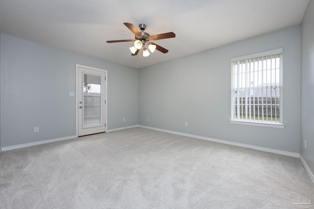 spare room featuring a ceiling fan, light carpet, a textured ceiling, and baseboards