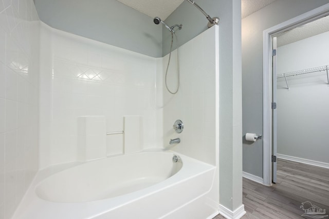 full bath with baseboards, shower / tub combination, wood finished floors, a walk in closet, and a textured ceiling