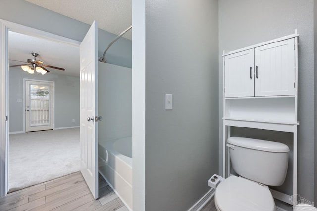 full bathroom with baseboards, a ceiling fan, toilet, a textured ceiling, and washtub / shower combination