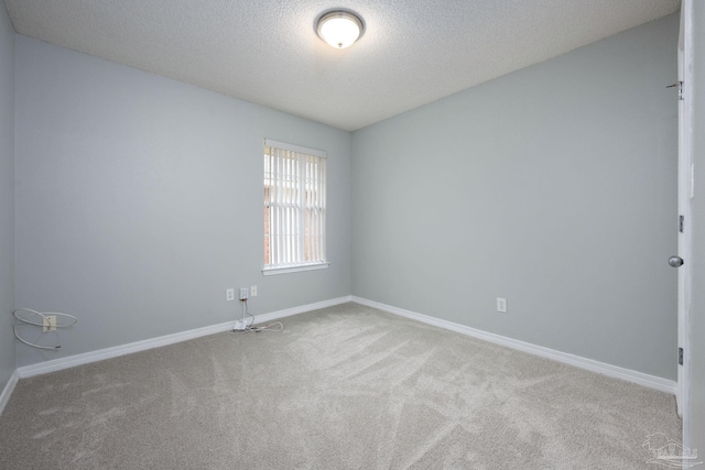 unfurnished room featuring a textured ceiling, carpet flooring, and baseboards