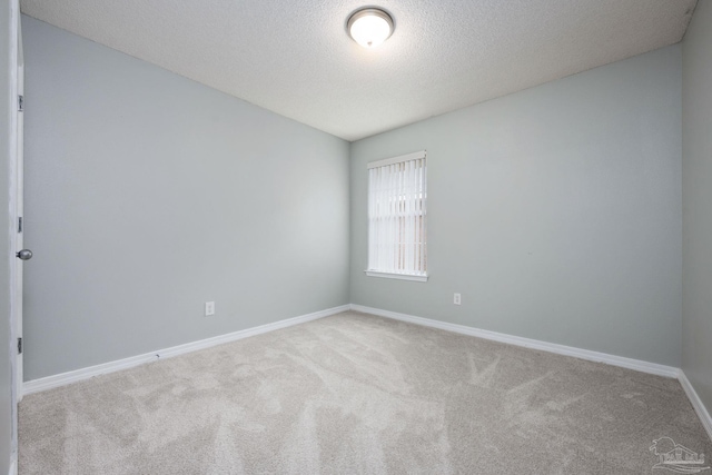 carpeted spare room with a textured ceiling and baseboards