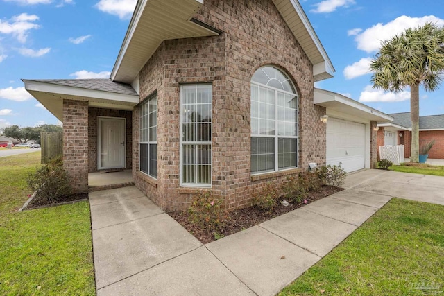 exterior space with a garage, concrete driveway, brick siding, and a yard