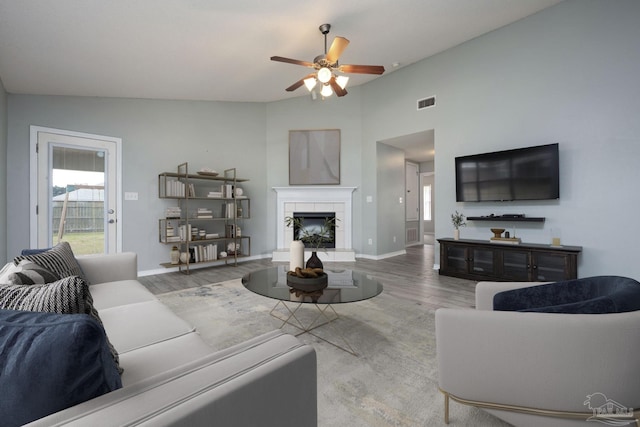 living room featuring baseboards, a fireplace, visible vents, and wood finished floors