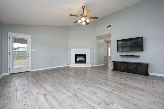 unfurnished living room featuring ceiling fan, a fireplace, visible vents, and wood finished floors