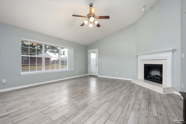 unfurnished living room featuring baseboards, lofted ceiling, ceiling fan, wood finished floors, and a fireplace