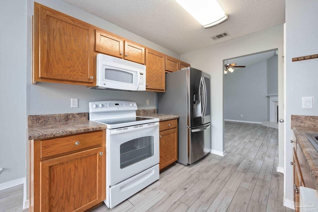 kitchen featuring a textured ceiling, ceiling fan, light wood-style flooring, white appliances, and visible vents