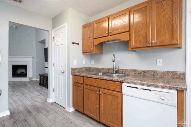 kitchen featuring light wood-type flooring, white dishwasher, a sink, and brown cabinets