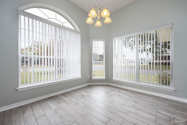 unfurnished dining area featuring baseboards, a chandelier, and wood finished floors