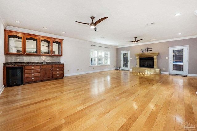 unfurnished living room featuring light hardwood / wood-style flooring, beverage cooler, crown molding, and ceiling fan