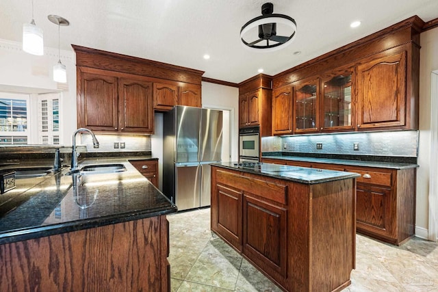 kitchen with stainless steel refrigerator, sink, hanging light fixtures, crown molding, and a center island with sink