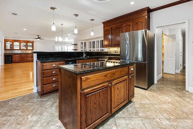 kitchen featuring stainless steel refrigerator, ceiling fan, sink, hanging light fixtures, and a kitchen island