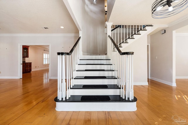 stairway featuring hardwood / wood-style floors and ornamental molding