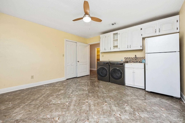 washroom featuring washer and dryer, ceiling fan, cabinets, and a textured ceiling