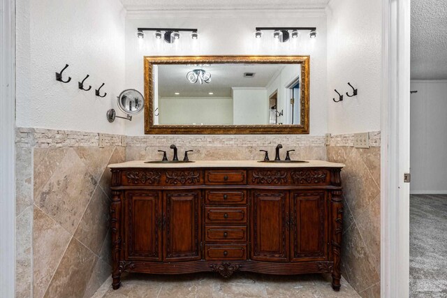 bathroom with a textured ceiling, vanity, tile walls, and ornamental molding