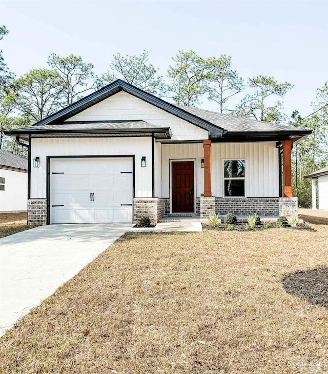 view of front facade with a front lawn, driveway, board and batten siding, an attached garage, and brick siding