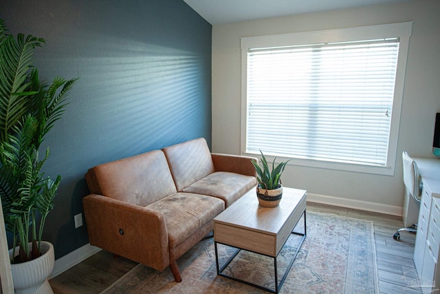 living area featuring a wealth of natural light, vaulted ceiling, baseboards, and wood finished floors