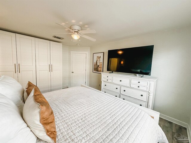 bedroom with baseboards, visible vents, a ceiling fan, wood finished floors, and a closet