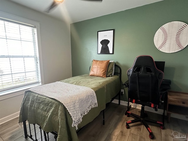 bedroom with multiple windows, baseboards, and wood finished floors