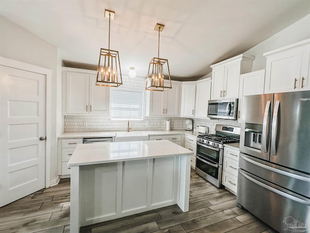 kitchen with appliances with stainless steel finishes, wood finish floors, a kitchen island, and backsplash