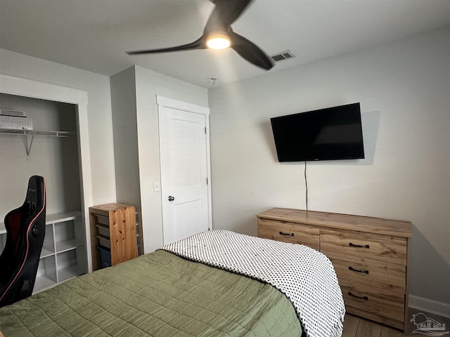 bedroom with baseboards, visible vents, ceiling fan, wood finished floors, and a closet