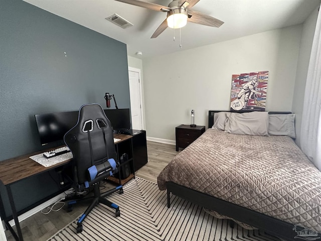 bedroom featuring baseboards, visible vents, ceiling fan, and light wood finished floors