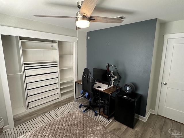 office with ceiling fan, visible vents, baseboards, and wood finished floors