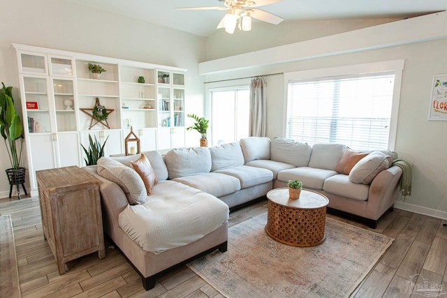 living area featuring vaulted ceiling, a ceiling fan, light wood-style flooring, and baseboards