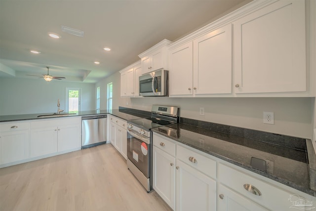 kitchen featuring white cabinetry, sink, ceiling fan, stainless steel appliances, and dark stone counters