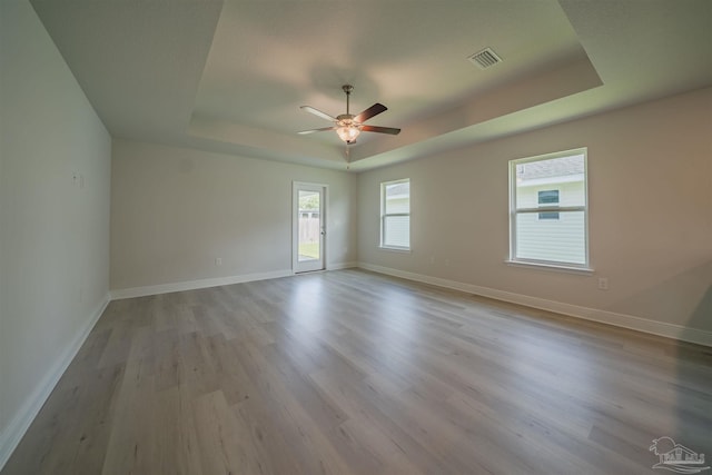 spare room featuring light hardwood / wood-style flooring, a raised ceiling, and ceiling fan