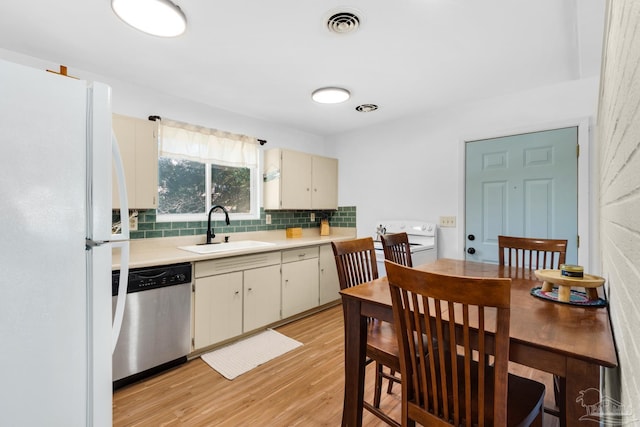 kitchen with sink, stainless steel dishwasher, white refrigerator, light hardwood / wood-style floors, and decorative backsplash