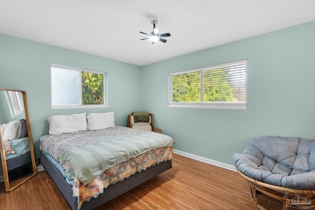 bedroom with multiple windows, ceiling fan, and hardwood / wood-style flooring