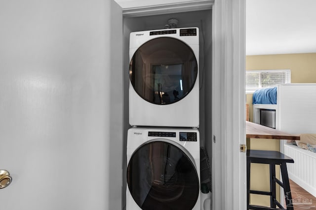 laundry room with hardwood / wood-style floors and stacked washer / drying machine