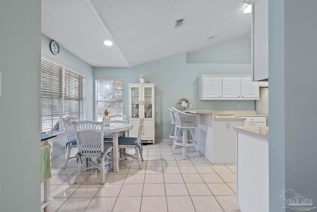 10738 Magnolia Ln, Lillian, AL 36549 - dining space featuring light tile patterned floors, baseboards, visible vents, vaulted ceiling, and a textured ceiling
