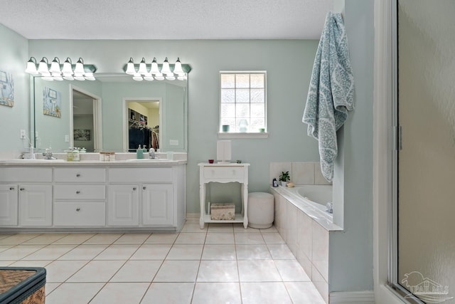 10738 Magnolia Ln, Lillian, AL 36549 - bathroom with tile patterned floors, a garden tub, a textured ceiling, and a sink